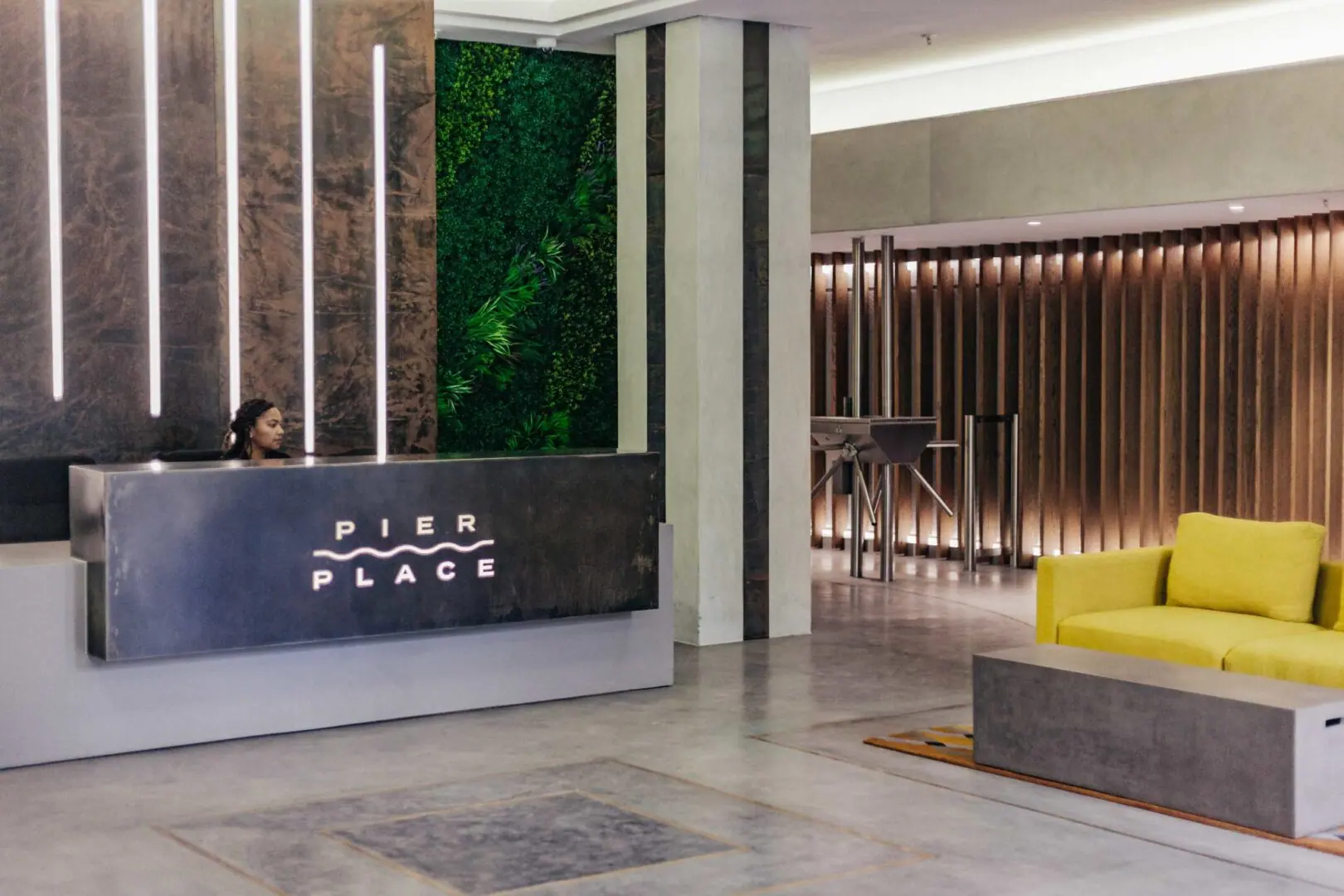 Reception area at Pier place with a wall of artificial plants behind the desk