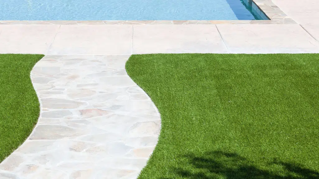 Artificial grass lawn next to a clear swimming pool